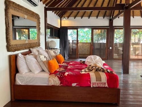 a bedroom with a bed and a mirror and windows at My happy place loft gili air in Gili Islands