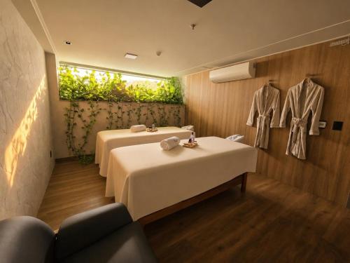 a room with two tables and a suit hanging on a wall at Sais Beach Living Hotel in Maceió