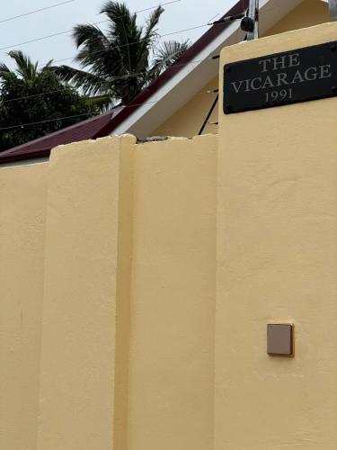 a sign on the side of a yellow building at The Vicarage in Lashibi