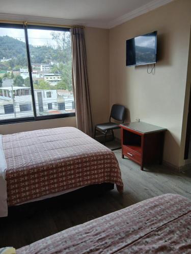 ein Hotelzimmer mit zwei Betten, einem Schreibtisch und einem Fenster in der Unterkunft Hotel Jomaley in Loja