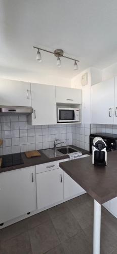 a white kitchen with a sink and a microwave at Studio Le Mûrier in Saint-Martin-dʼHères