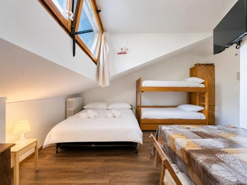 a attic bedroom with two beds and a window at Hostdomus - Green Valley in Borgata Sestriere