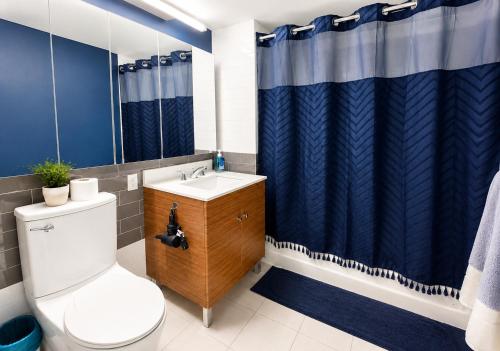 a bathroom with a toilet and a blue shower curtain at Studio apart Time Square in New York
