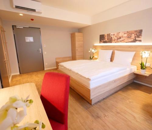 ein Hotelzimmer mit einem Bett und einem roten Stuhl in der Unterkunft KELKO 1A Hotel in Kehl am Rhein