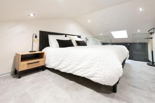 a bedroom with a large white bed and a night stand at Studio Le Quartz tout inclus petitdéjeuner in Éloyes