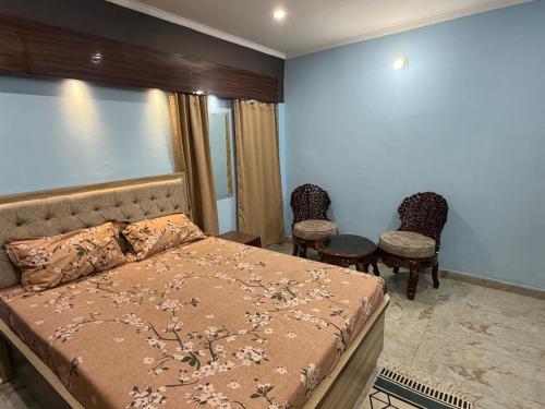 a bedroom with a bed and two chairs at Prakash Bhawan in Darbhanga