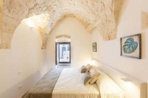 a bedroom with a large bed with a stone wall at Casa Leo with Jacuzzi in Ostuni