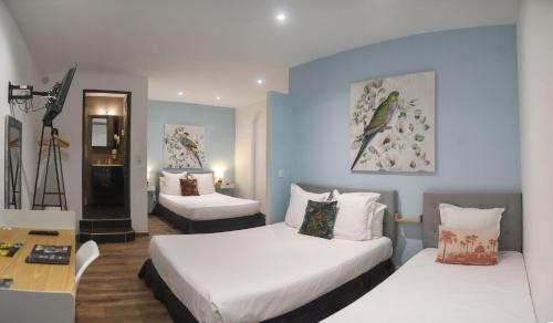 a hotel room with two beds and a table and a desk at Hôtel Du Palais Bastia Centre in Bastia