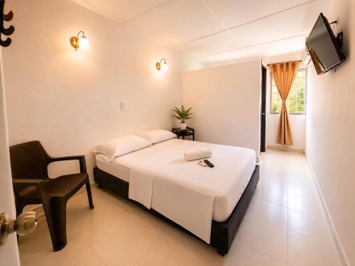 a bedroom with a bed and a chair and a television at Renta Mar in Barranquilla