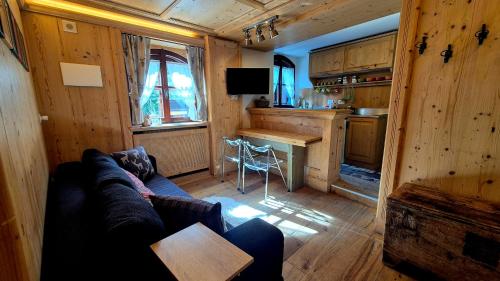 a living room with a couch and a table and a kitchen at Bilocale Ristrutturato in Madesimo