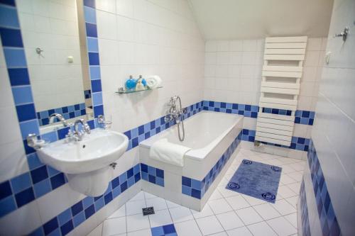 a blue and white bathroom with a tub and a sink at Hotel Sutoris in Bochnia