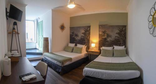 a hotel room with two beds and a tv at Hôtel Du Palais Bastia Centre in Bastia