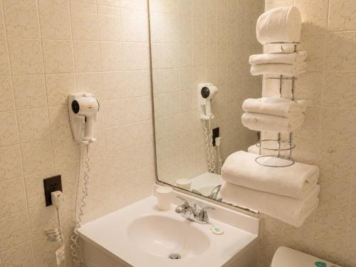a bathroom with a sink and a mirror and towels at Top Notch Motel in Wiarton