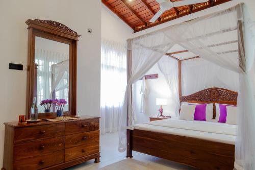 a bedroom with a canopy bed and a wooden dresser at Kasitha Ocean View Villa - Matara Beach Road in Matara
