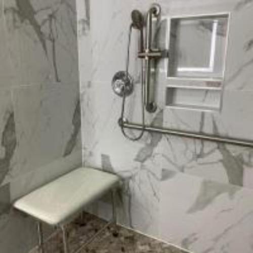 a shower with a bench in a bathroom at Americas Express Inn Rocky Mount in Rocky Mount