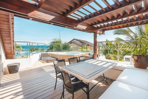 an outdoor deck with a table and chairs and the ocean at Gorgeous PH at Puerto Bahia in Santa Bárbara de Samaná