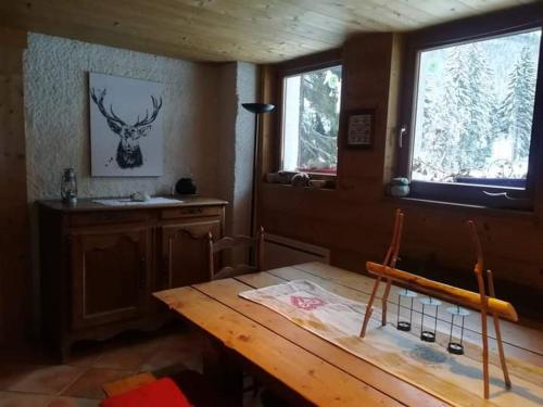 a dining room with a wooden table and two windows at chambre pour 2 à 4 personnes ,balcon in Mont-Saxonnex