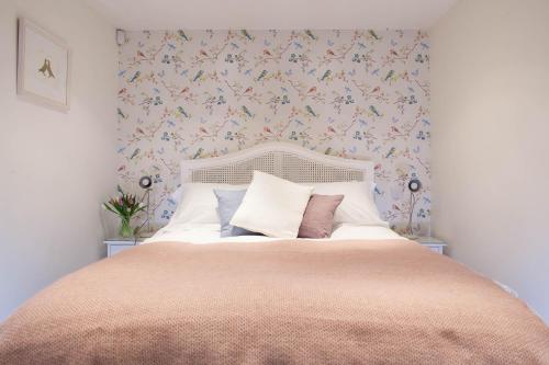 a bedroom with a large bed with floral wallpaper at Fig Cottage, near Bradford on Avon and Bath in Holt
