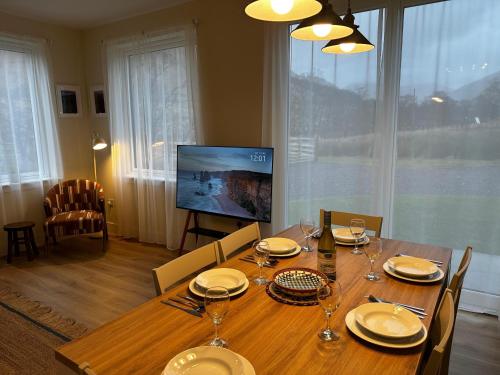 a dining room with a wooden table and a television at Auch - Cottages in Bridge of Orchy