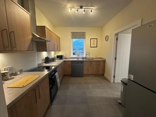 a kitchen with wooden cabinets and a large window at Auch - Cottages in Bridge of Orchy
