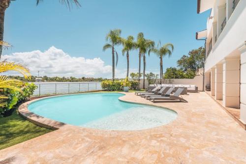 a swimming pool with lounge chairs and palm trees at Seaside Bliss with pool and spectacular view in Las Minas