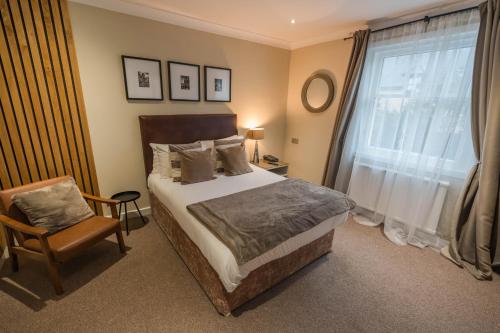 a bedroom with a bed and a chair and a window at The Kirkhouse Inn in Strathblane