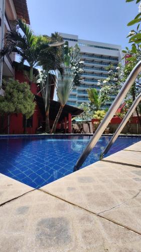a swimming pool with palm trees and a building at Pousada Legno Bossa Nova in Maceió