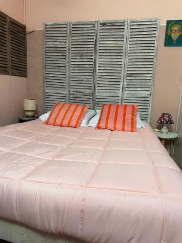 a large bed with orange and white pillows on it at La chambre de Joséphine in Royan
