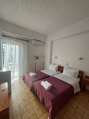 a bedroom with two beds and a large window at Pasiphae - Rooms for rent in Agia Galini