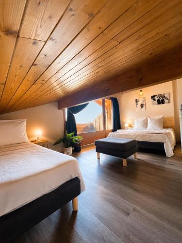 a bedroom with two beds and a wooden ceiling at Chalet Hotel Alpaka in Châtel