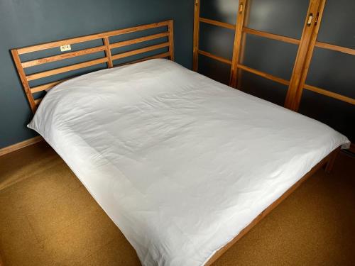 a bed with white sheets on it in a room at Aluksne city nest in Alūksne