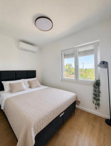 a white bedroom with a bed and two windows at Panorama Krizevac in Međugorje