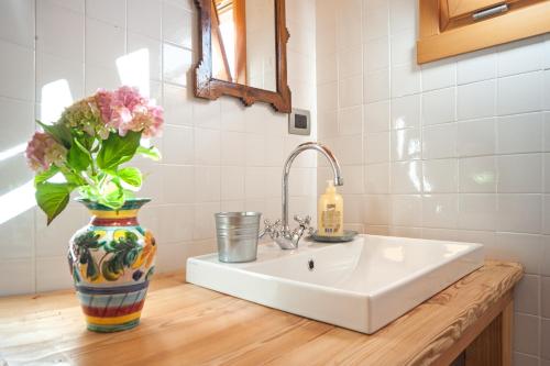 La salle de bains est pourvue d'un lavabo avec un vase de fleurs sur un comptoir. dans l'établissement Agriturismo Serec, à Angolo Terme