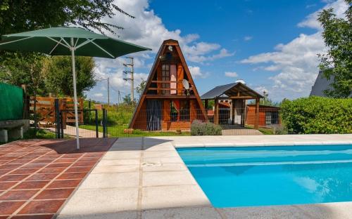 a house with a pool and an umbrella at Cabañas Don Luis in Valle Hermoso