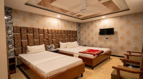 two beds in a room with a tv at Standard Elite Palace inn Hotel in Islamabad