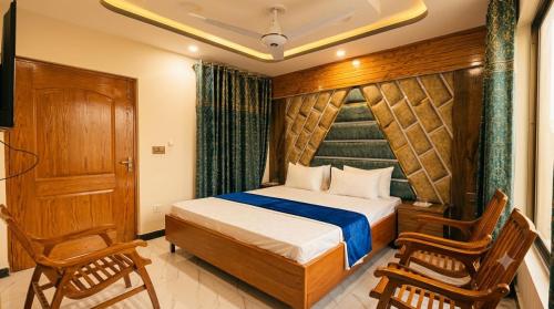 a bedroom with a bed and two chairs and a television at Standard Elite Palace inn Hotel in Islamabad