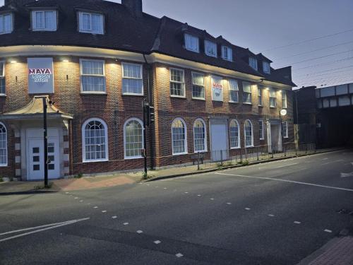 a brick building with a sign on the side of the street at Maya Hotel in Luton