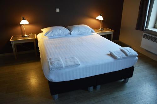 a bedroom with a large bed with two lamps on two tables at Ambassador Suites Antwerp in Antwerp