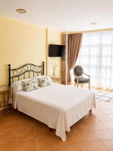 a bedroom with a large white bed and a chair at Holibai Misiño, Estudio para dos en Baiona in Baiona