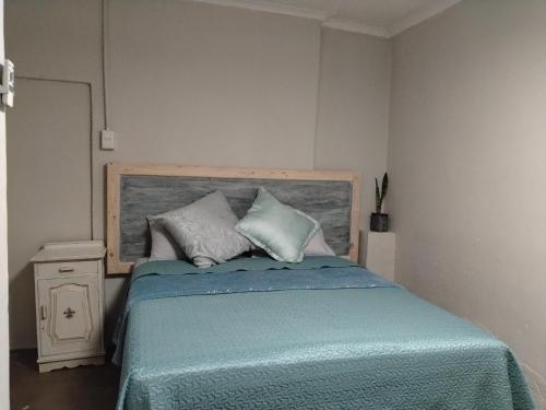 a bedroom with a bed with a wooden headboard and pillows at Avalon Cottages in Barberton