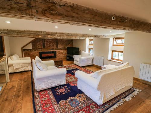 a living room with white chairs and a fireplace at Netherend Barn in Colwall