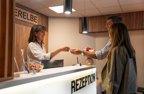 Ein Mann und eine Frau schütteln sich an einem Empfangstisch die Hände. in der Unterkunft Hotel Süderelbe in Hamburg