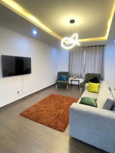 a living room with a couch and a flat screen tv at Maisonette near Alpha Beach in Ibeju