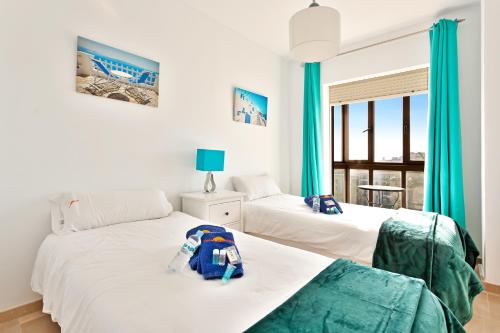two beds in a room with green curtains at CasaBella Marina Duquesa in Manilva
