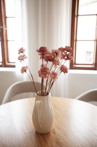 a white vase with pink flowers sitting on a table at Pension Marie in Český Krumlov