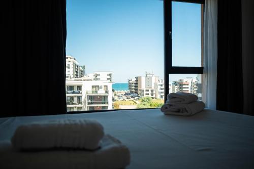 a bedroom with two towels on a bed with a large window at Kazeboo Bed & Breakfast in Mamaia Sat/Năvodari