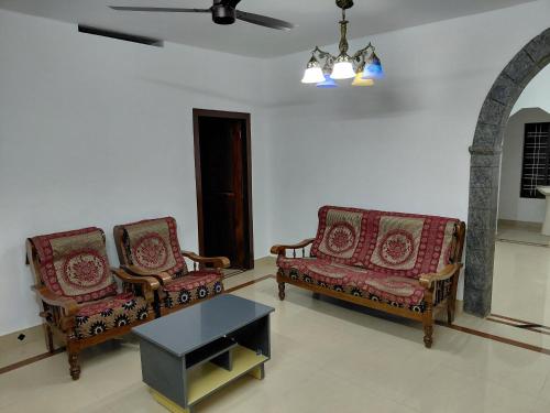 two chairs and a coffee table in a living room at Casa Inn Homestay in Munnar