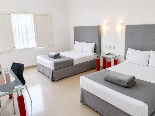 ein Hotelzimmer mit zwei Betten und einem Schreibtisch in der Unterkunft Zar Culiacan in Culiacán Rosales