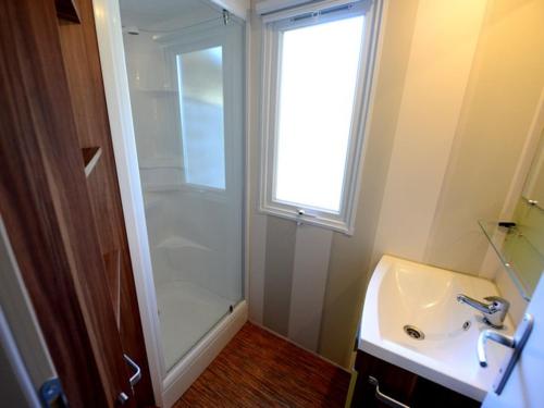 a bathroom with a shower and a sink and a window at Camping Cascade Aveyron in Saint-Rome-de-Tarn