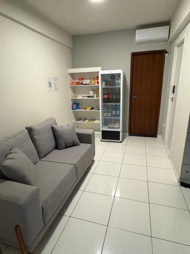 a living room with a couch and an open refrigerator at Quarto com Ar Condicionado e banheiro no centro in Montes Claros